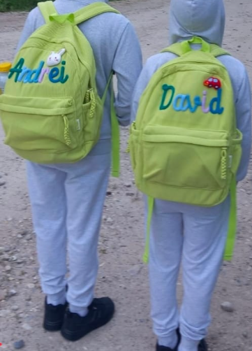 Two brothers wearing lime green backpacks with Andrei and David embroidered